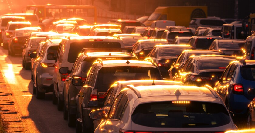 Cars in bumper-to-bumper traffic at sunset.