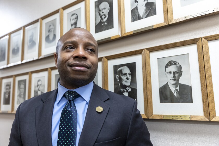 Milwaukee Mayor Cavalier Johnson standing in front of portraits of his predecessors.