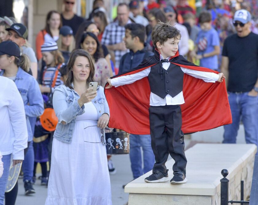 a boy dressed as a vampire stands over a crowd