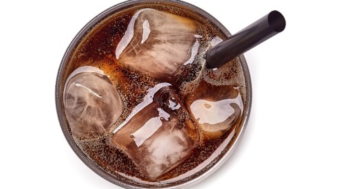 Soda in a glass with ice and a straw.