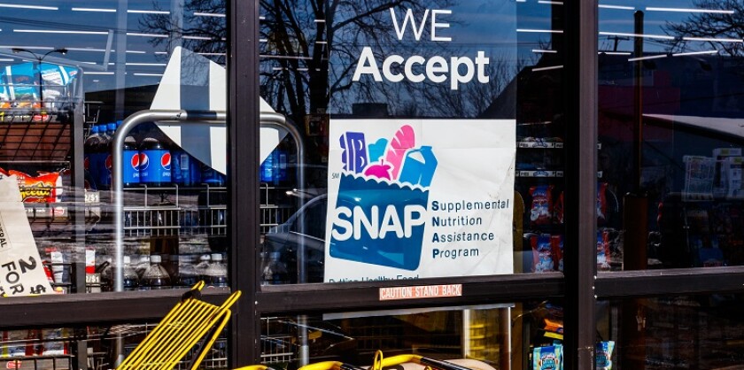 A sign in a storefront window that says "We Accept SNAP (Supplemental Nutrition Assistance Program)."