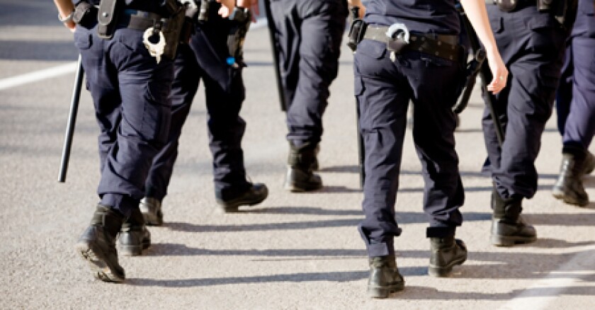 Tow rows of police officers walking away from the camera down a street.
