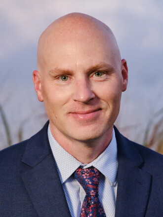 Dusty Borchardt headshot smiling in a dark blue suit.