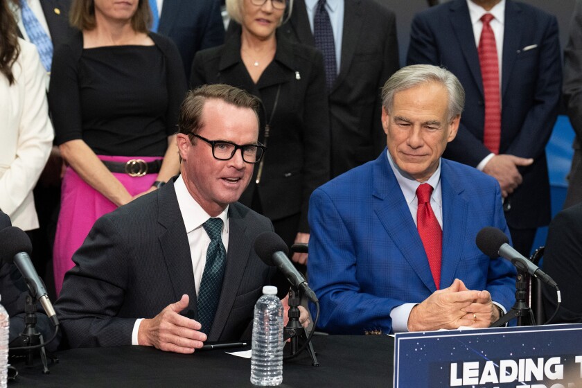 Speaker of the Texas House of Representatives Dade Phelan and Texas Gov. Greg Abbott sitting behind a table speaking into microphones.