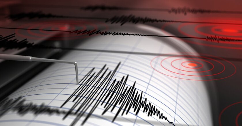 Close-up of a seismograph measuring earthquake activity with red lights in the background to indicate an alarm.
