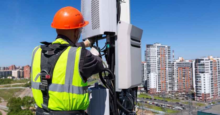 An engineer working on telecommunications equipment on a utility pole.