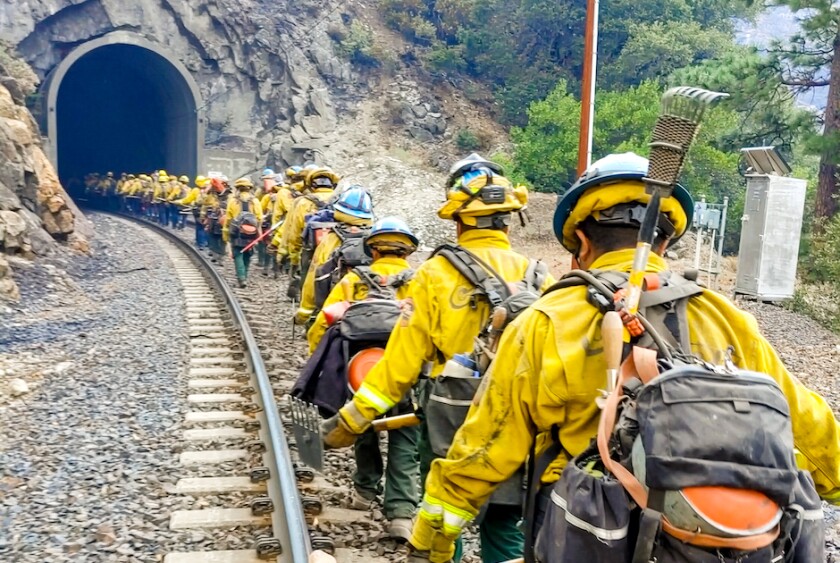 A CCC crew hiking along railroad tracks into a tunnel.