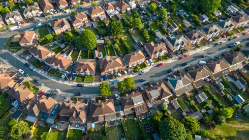 Aerial view of houses lining each side of a street in a suburb.