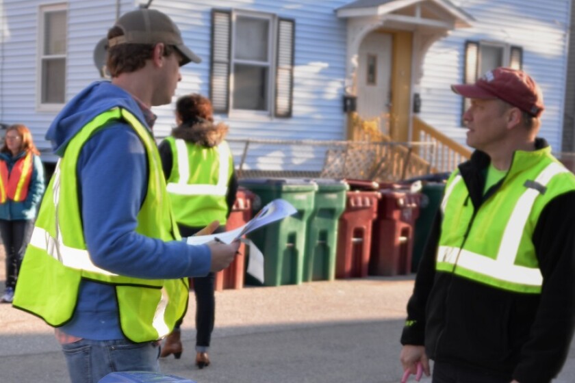 Two men talk among recycling bins