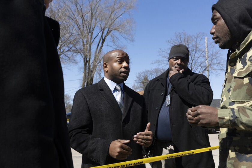 Milwaukee Mayor Cavalier Johnson speaking to two other people in front of yellow caution tape.