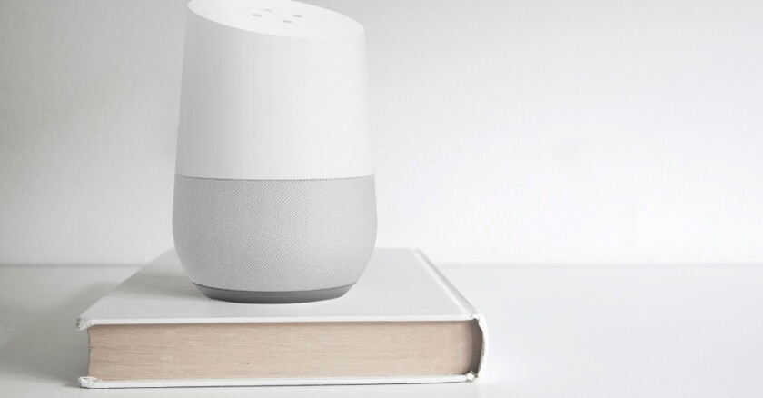 Google Home smart speaker on a book on a shelf