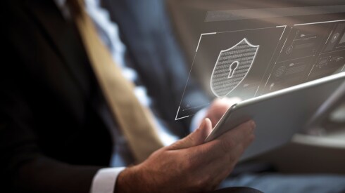 man in suit holding a tablet with an overlay of a lock suggesting cybersecurity
