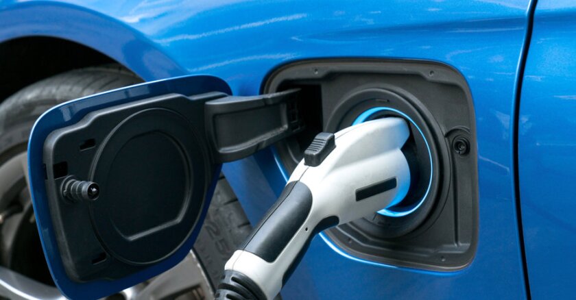 Close-up of an EV charging cable plugged into a blue vehicle.