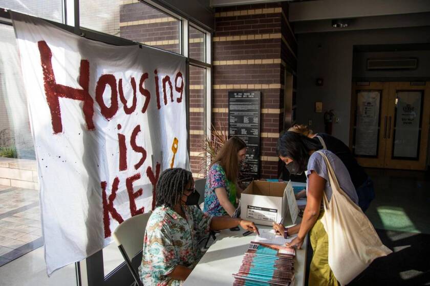 people check in to a Lexington, Ky., town hall meeting in front of a banner that reads "Housing is Key"